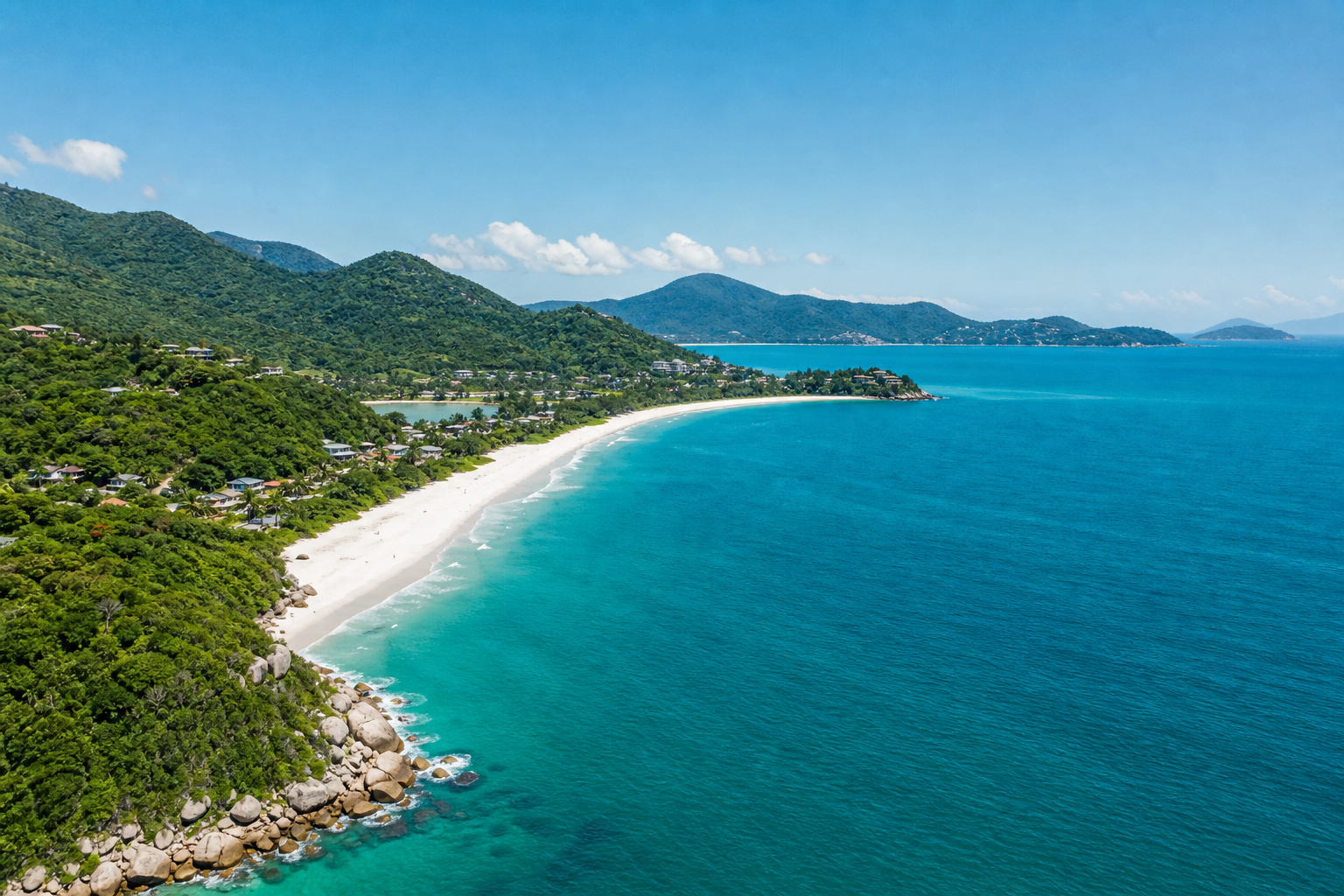 Vista aérea de una playa de Florianópolis con arena blanca, mar azul, vegetación y colinas al fondo en un día soleado.