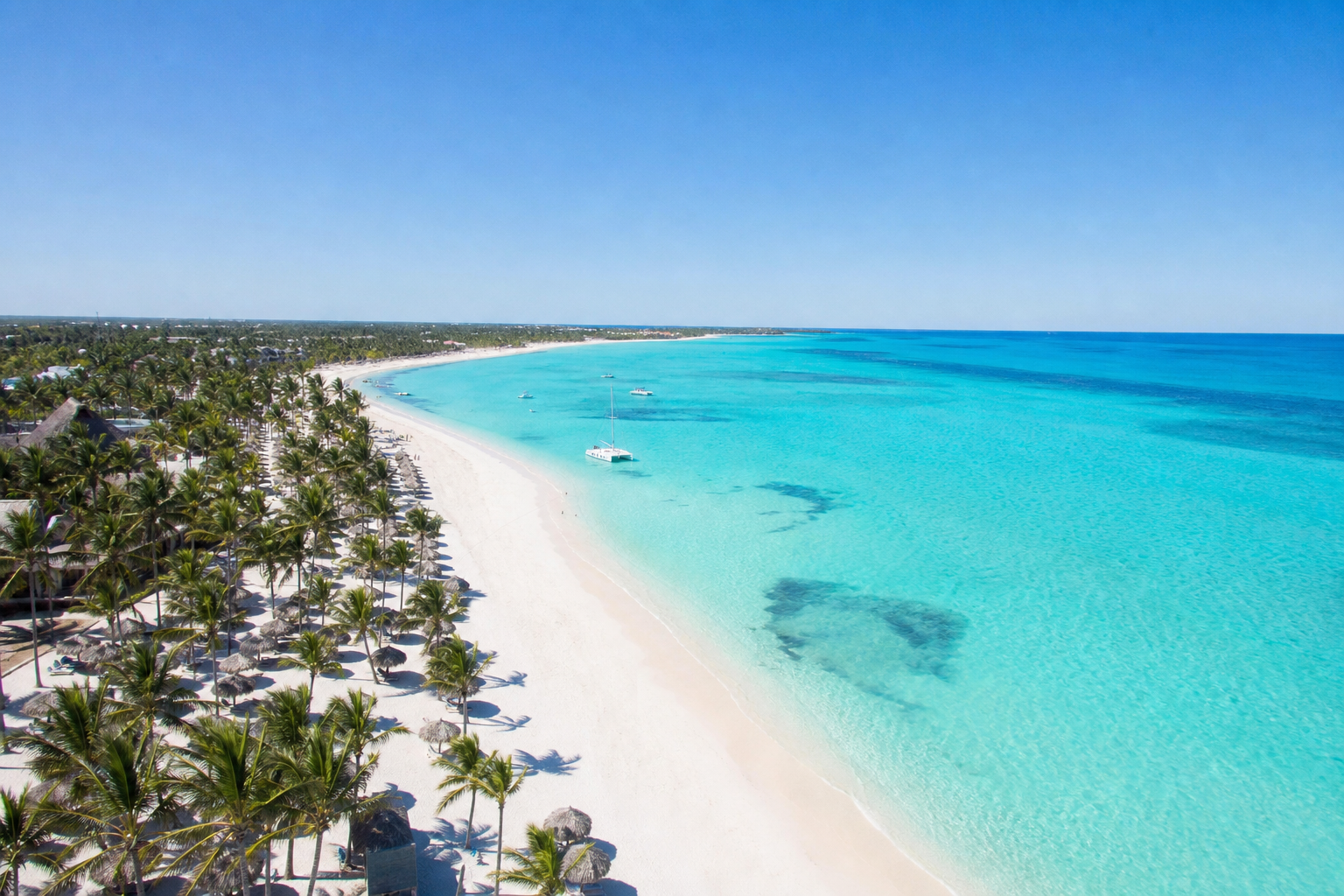 Vista aérea de las playas de Punta Cana con arena blanca, palmeras y aguas turquesa del Caribe en un día soleado.